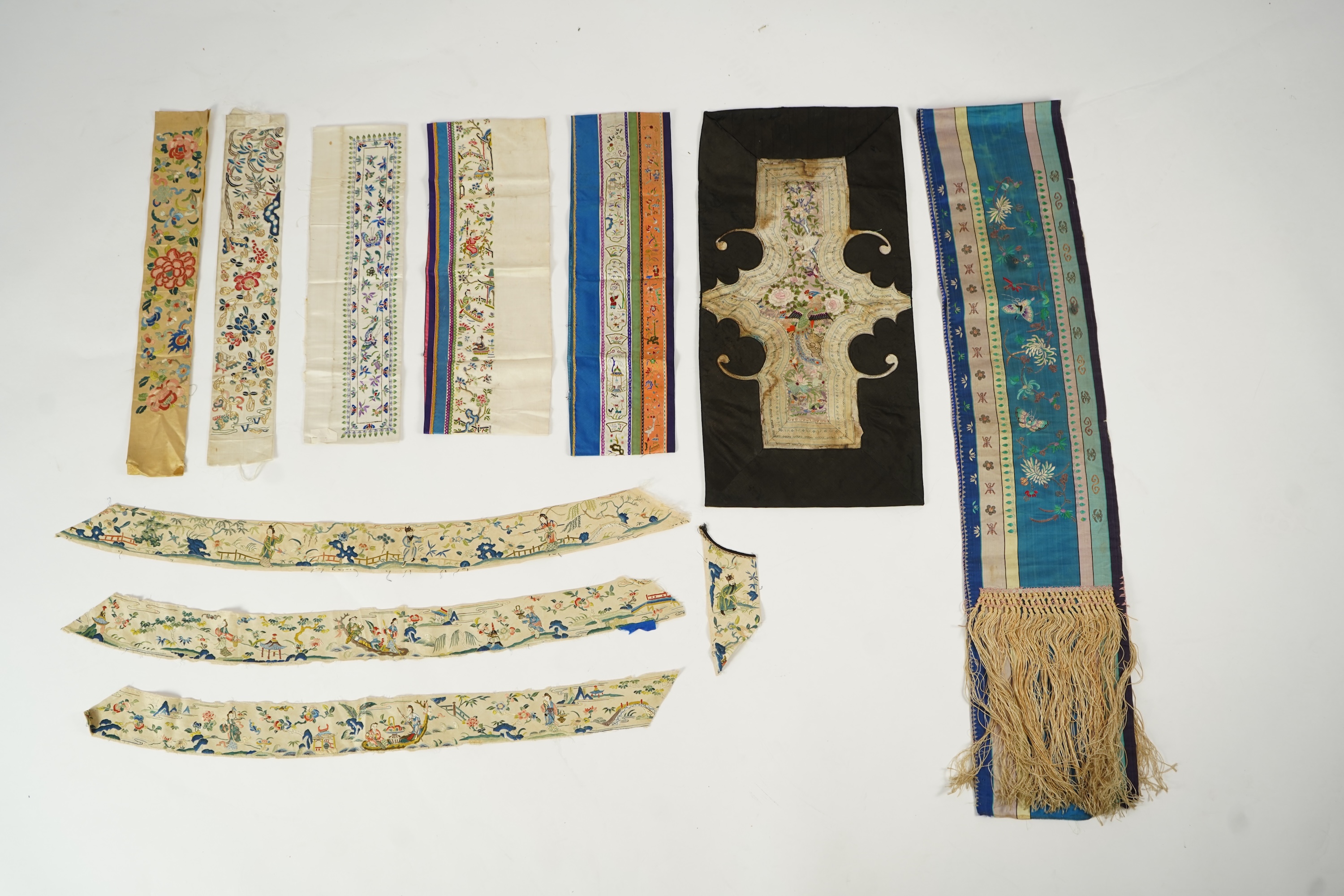 A Chinese embroidered silk panel of uncut robe borders, eleven similar sleeve panels and two other items, late Qing dynasty